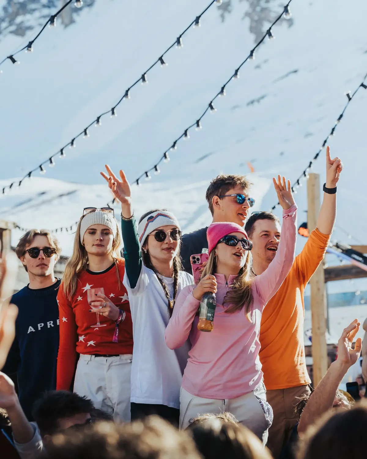 Members in ski gear cheering with drinks at an outdoor apres party