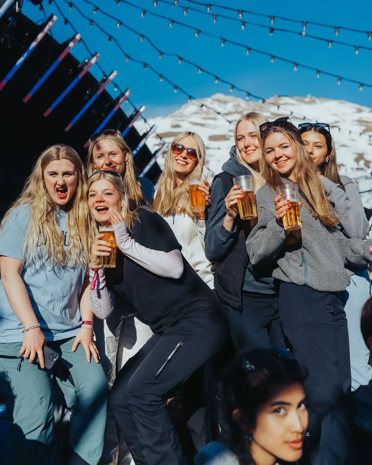 Group of members laughing with drinks at an apres bar in the snow