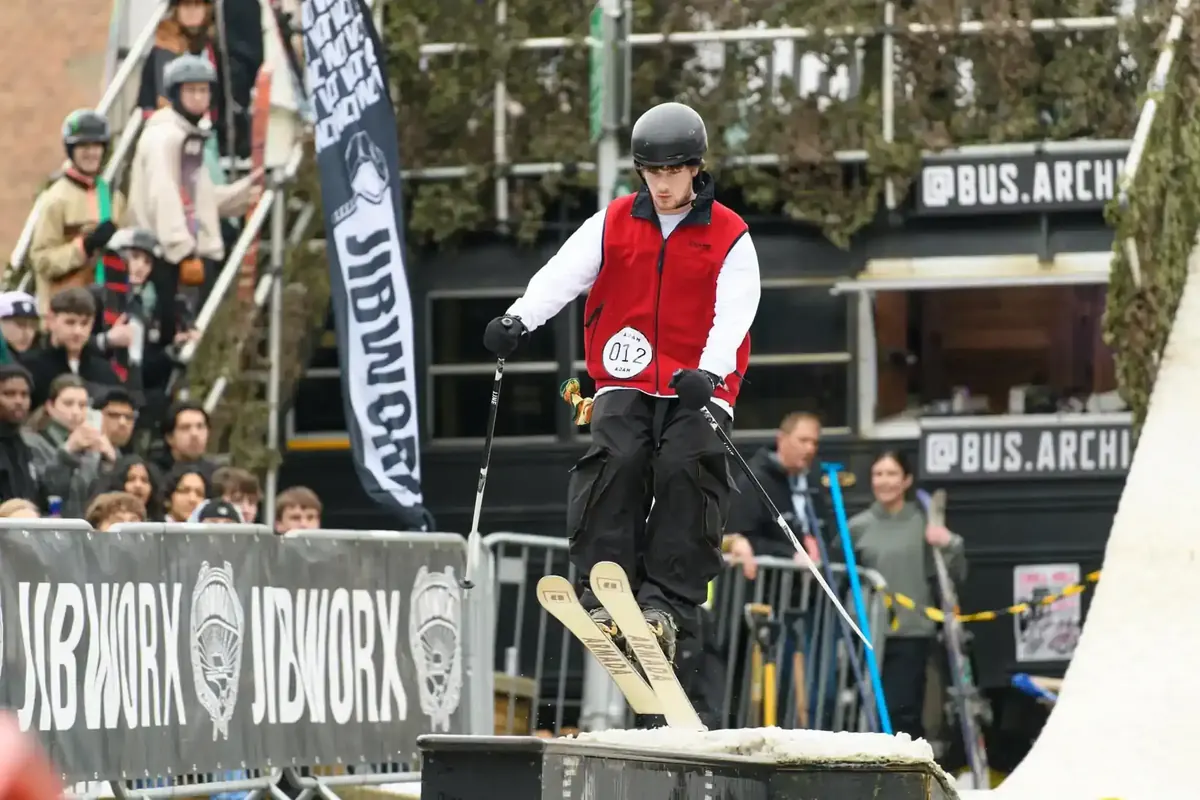 Skier sliding a box rail at Chill Hill as spectators watch from behind the barriers