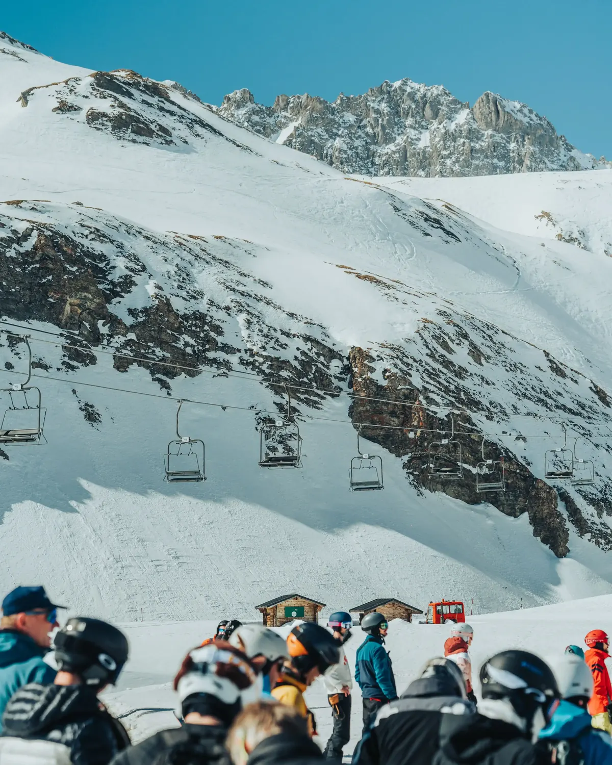 Skiers gathered at the top of a lift with a snowy bowl behind them