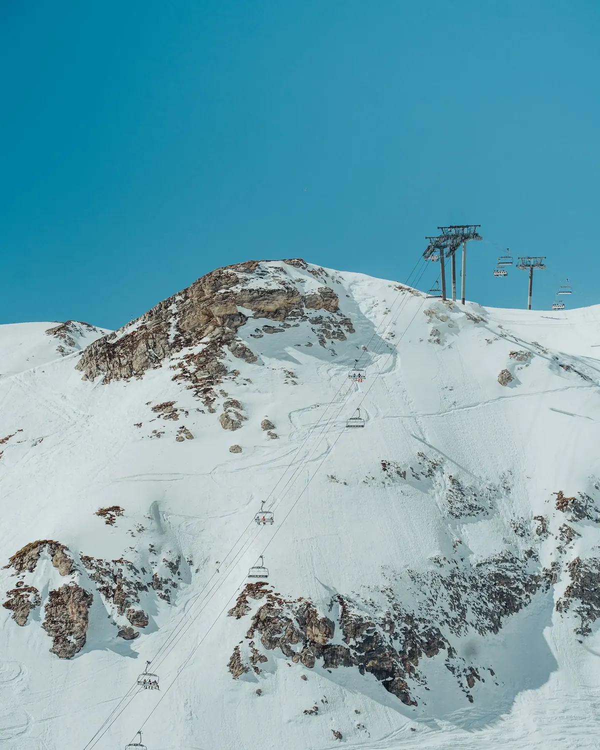 Rocky summit and lift pylons under a deep blue sky