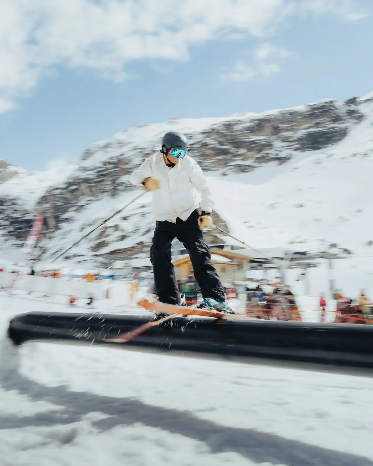 Snowboarder sliding a rail on the park line above the resort