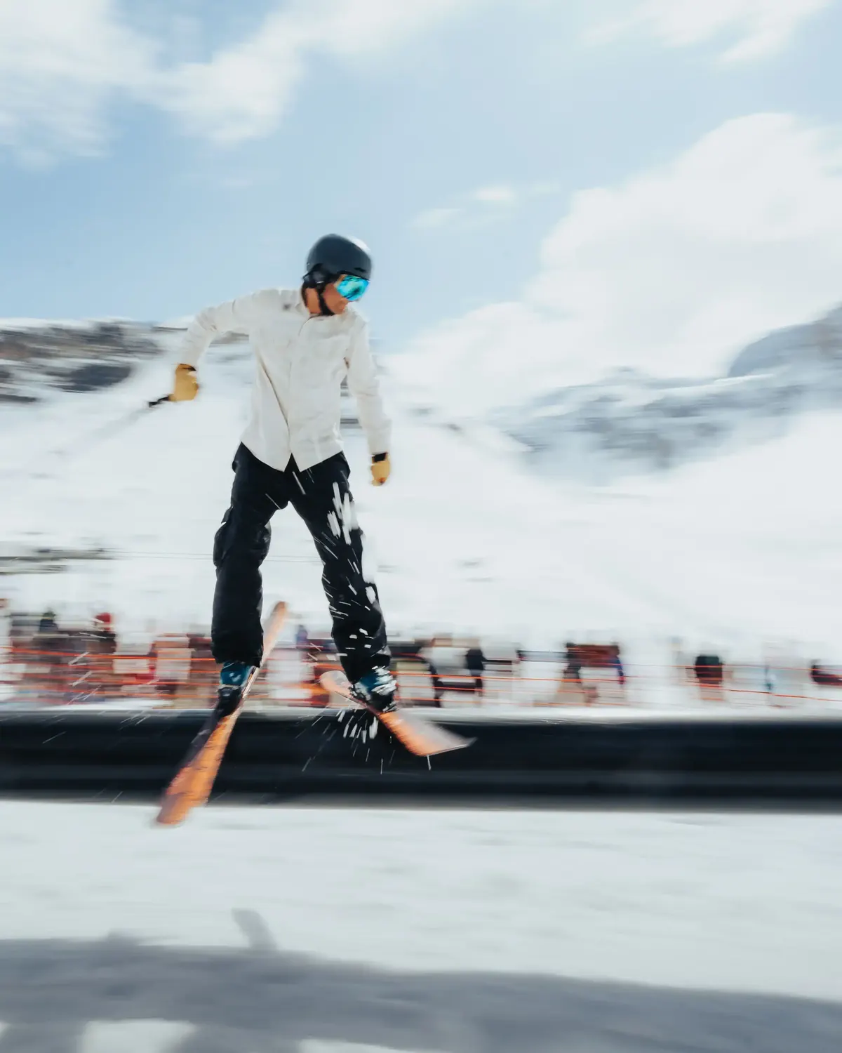 Skier balancing along a park rail, mountains behind