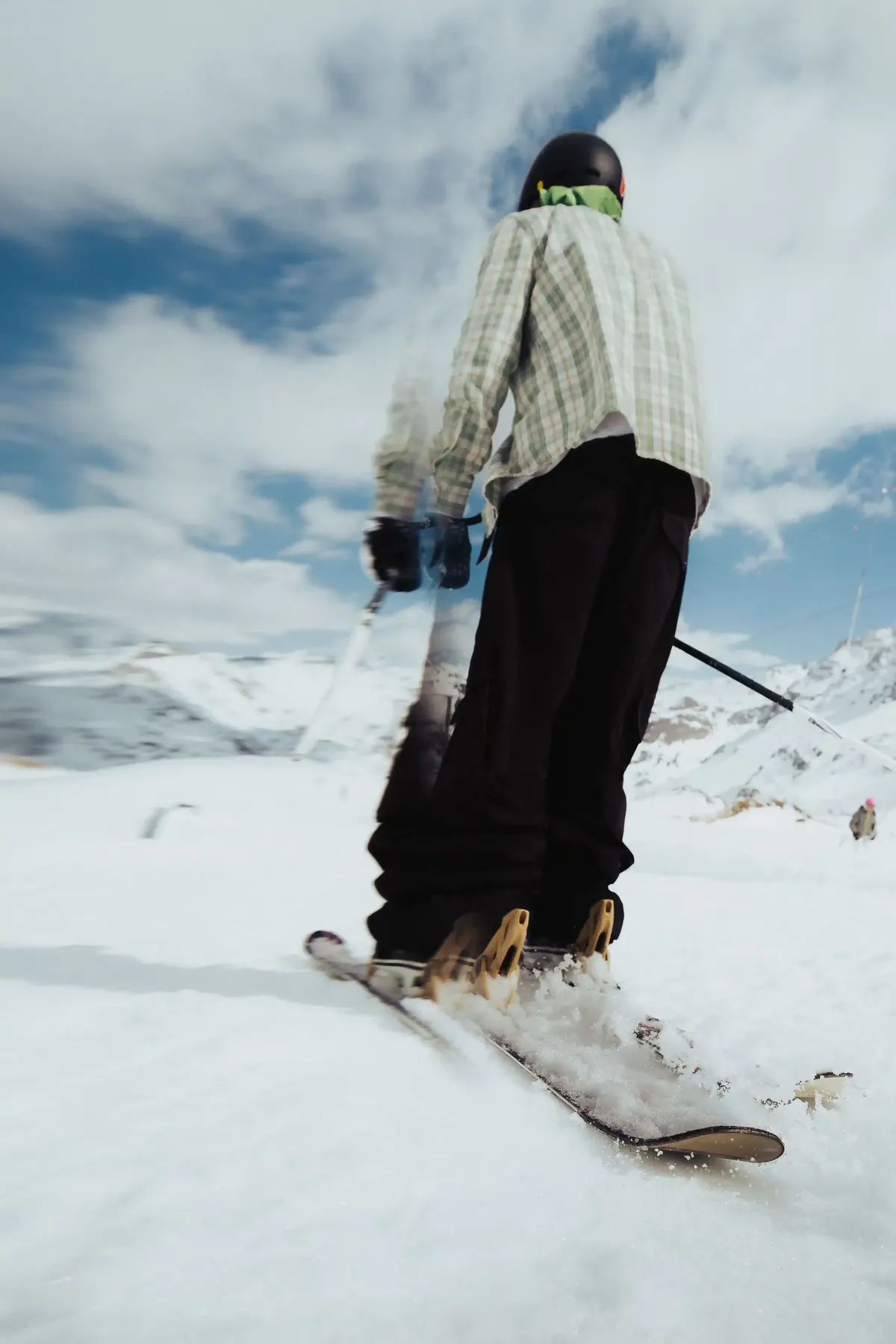Snowboarder riding across a snowy slope under a bright sky