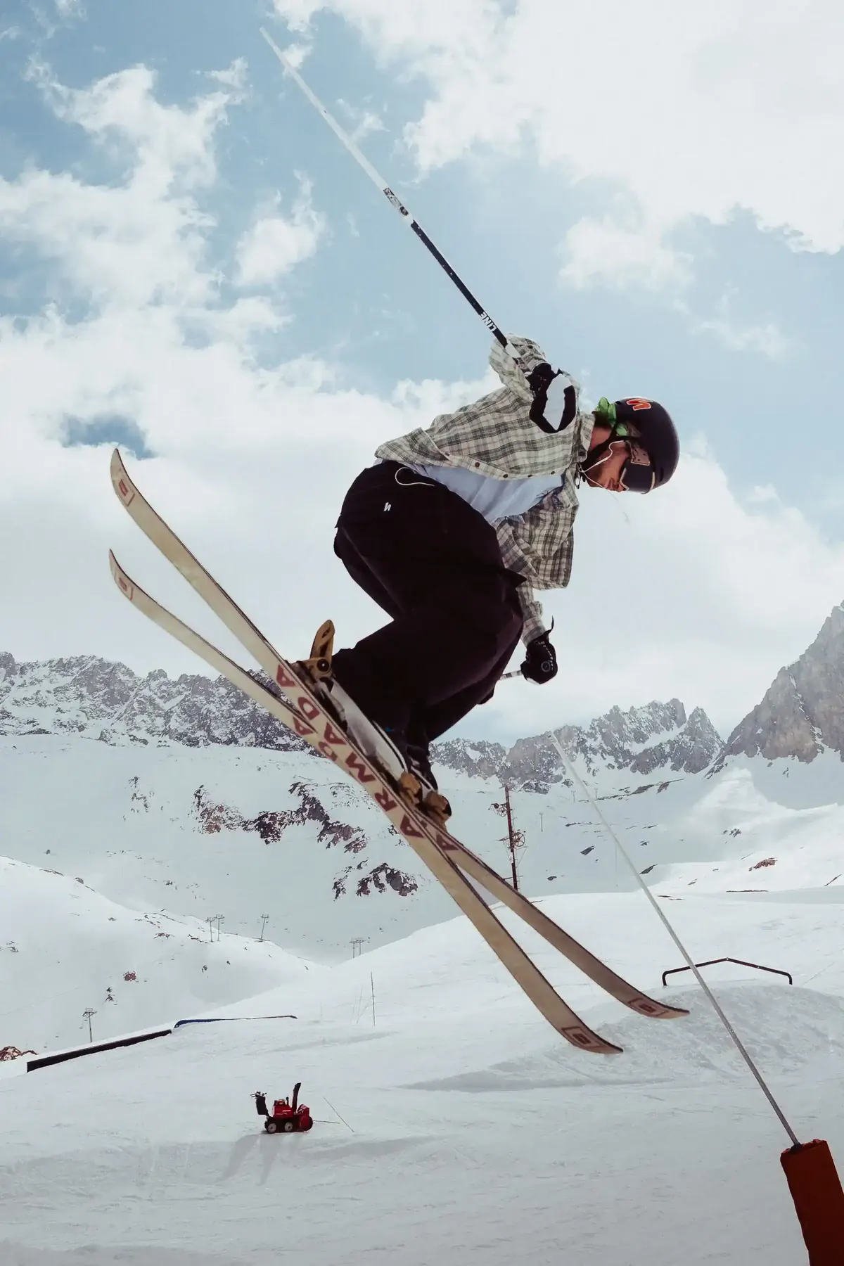 Skier boosting off a jump with the mountains behind