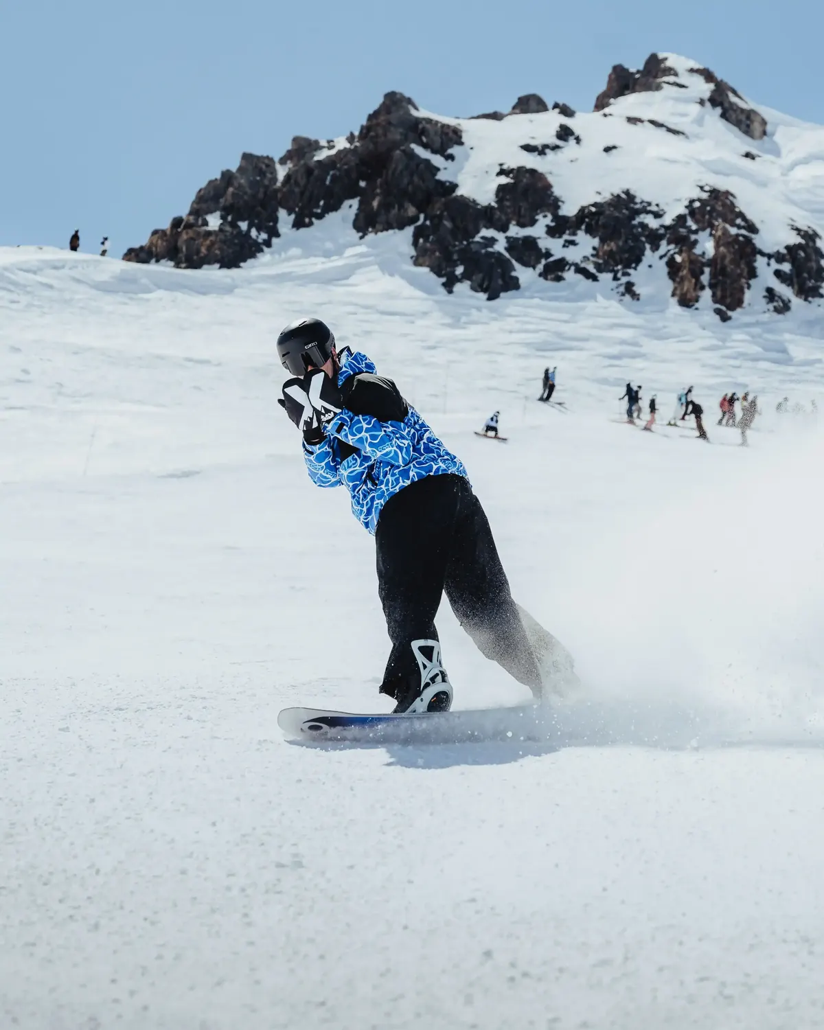 Snowboarder carving a turn below a rocky ridgeline